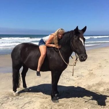 Debbie sitting on her horse at the beach